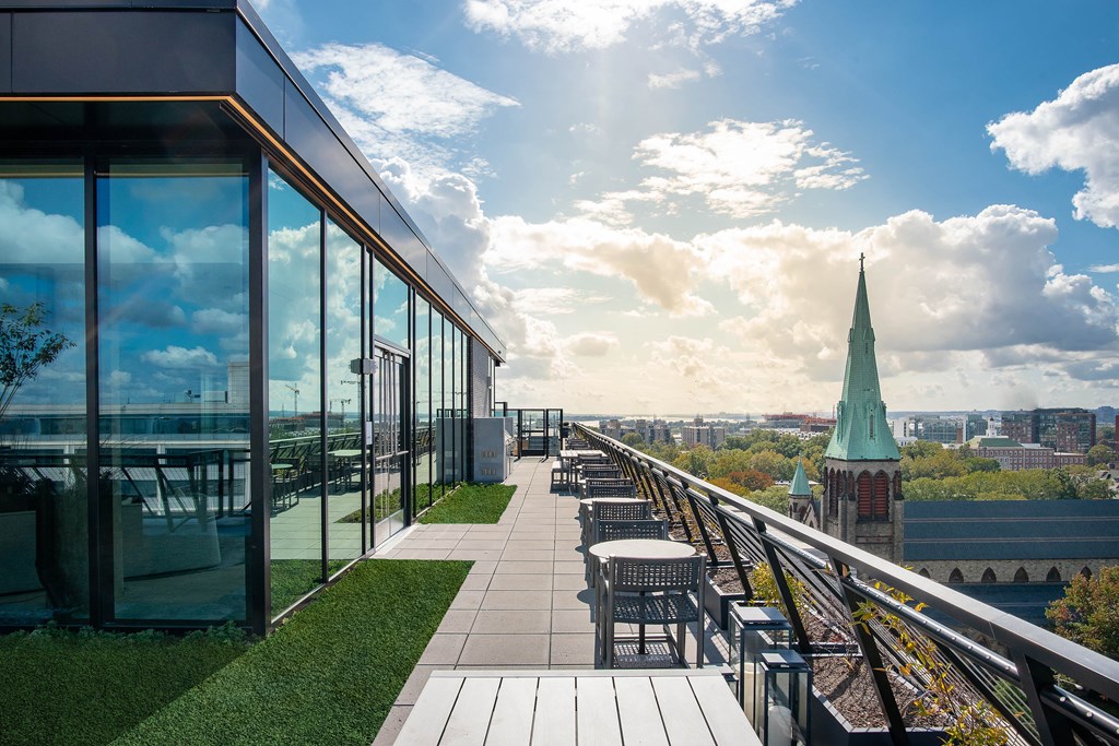 A modern building with a glass facade and a green spire in the background.