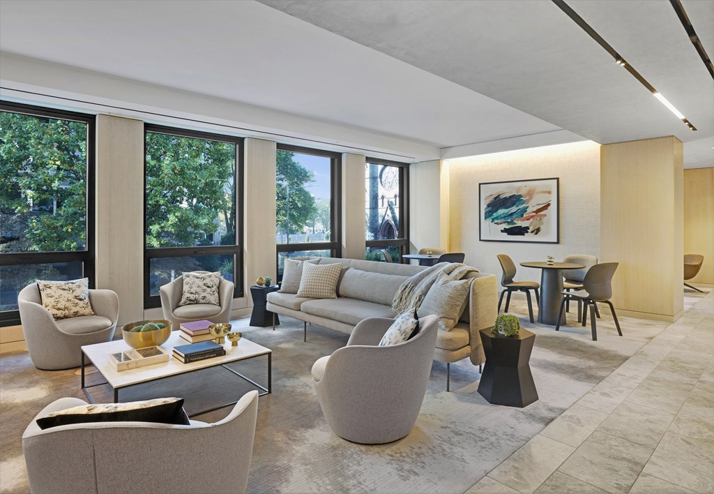 A living room with a large window and a painting on the wall.