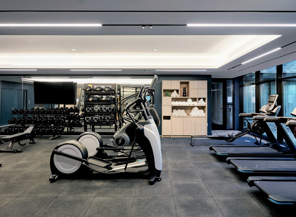 A modern gym with treadmills, elliptical machines, and a rowing machine.