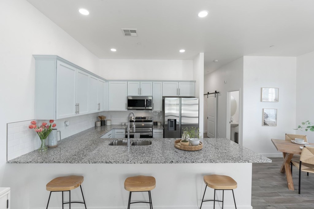 A kitchen with a granite countertop and stools.