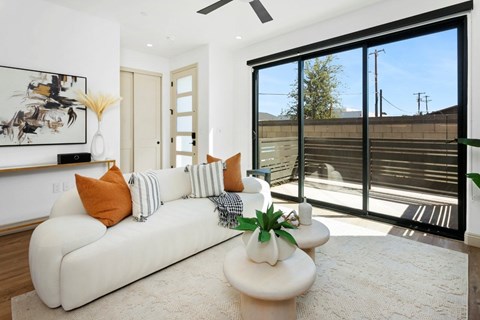A living room with a white couch and a painting on the wall.