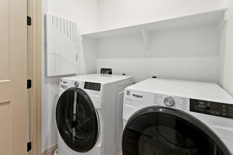 Two white Whirlpool washing machines in a laundry room.