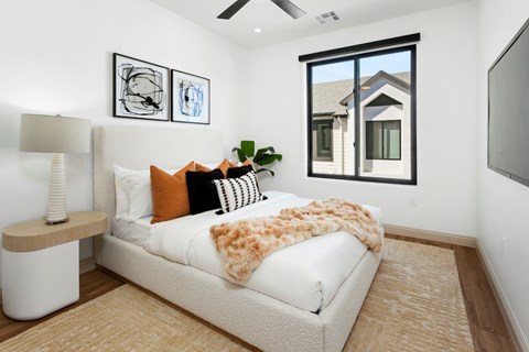 A bedroom with a large bed and a window overlooking a house.
