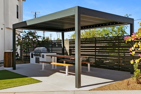 A picnic area with a table and benches under a shelter.