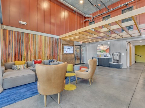 A modern living room with a grey sofa, yellow chairs and a striped wallpaper.