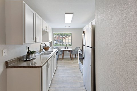 A kitchen with white cabinets and a wooden floor.