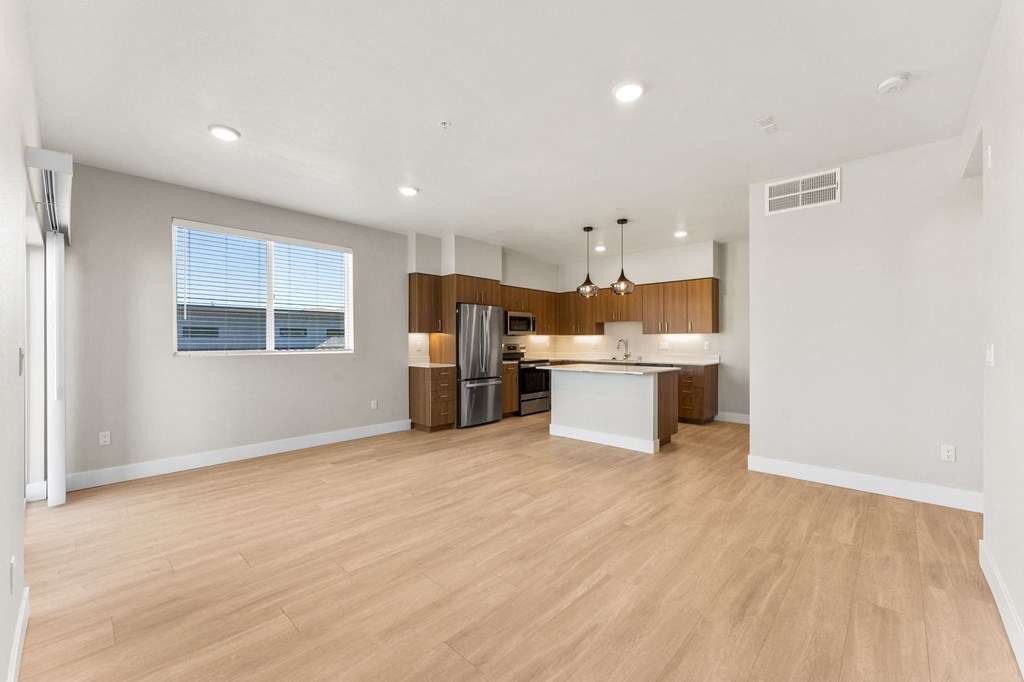 an open kitchen and living room with wood flooring and a large window