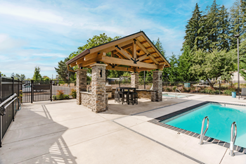 A pool area with a wooden pavilion and a stone pillar.