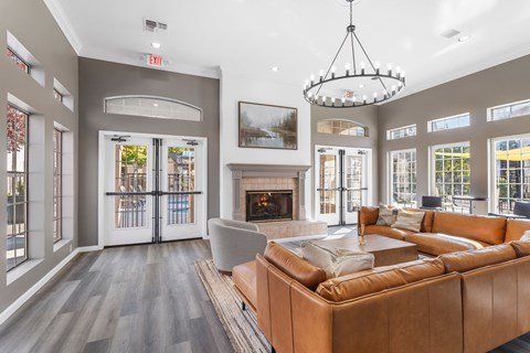 A living room with a brown leather couch and a chandelier.