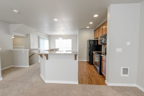 A kitchen with a black refrigerator and wooden cabinets.