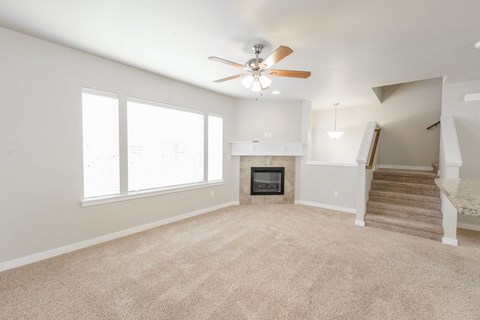 A living room with a fireplace and a staircase.