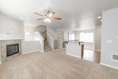 A living room with a fireplace and a fan on the ceiling.