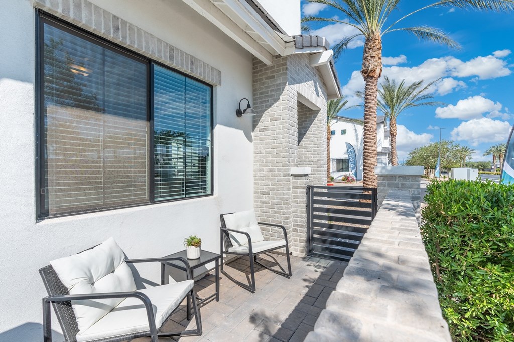 A patio with a table and chairs is in front of a house.