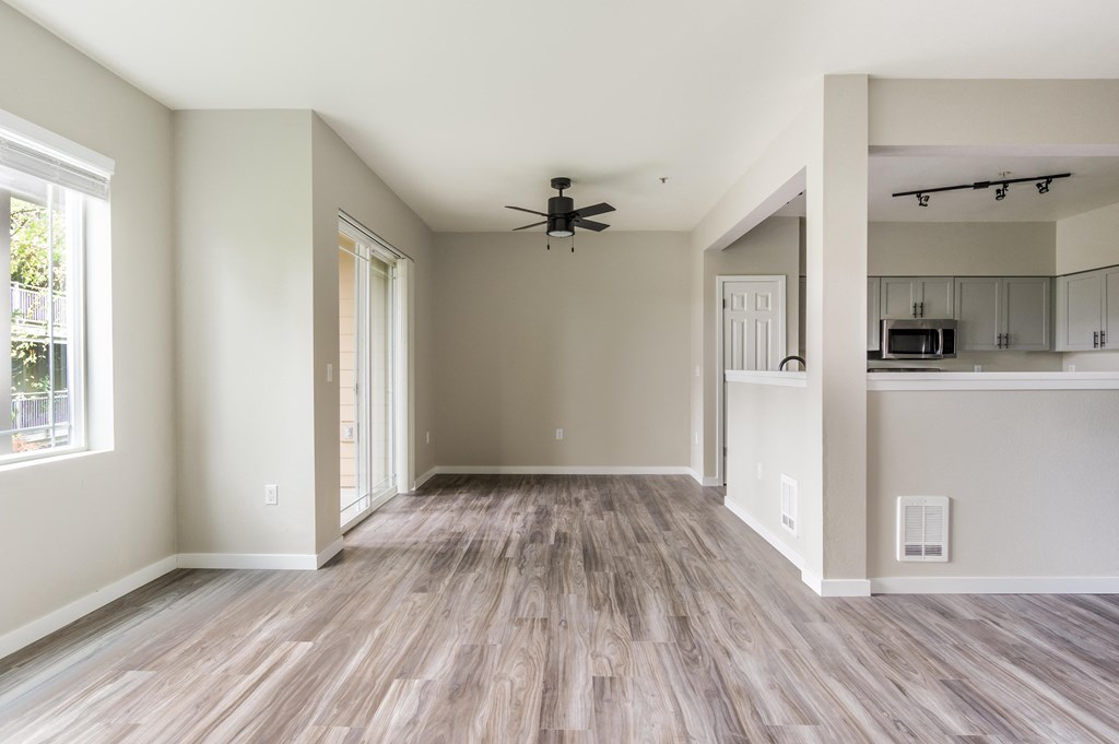 an empty living room with a ceiling fan