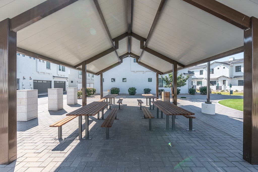 A covered outdoor seating area with benches and tables.