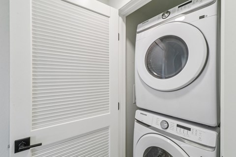 A white washing machine is stacked on top of another in a small space.