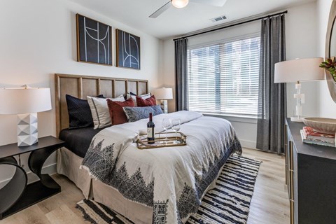 A bedroom with a large bed and a window with blinds.