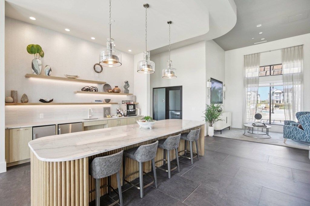 A modern kitchen with a curved island and bar stools.