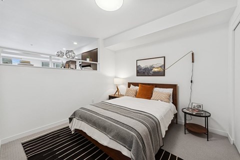 A bedroom with a bed, nightstand, and a picture on the wall.