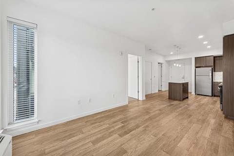 A spacious living room with wooden flooring and white walls.