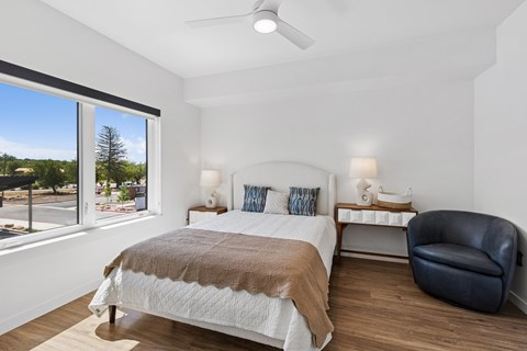 A bedroom with a large bed and a chair.