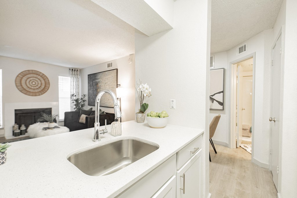 a kitchen with white cabinets and a sink and a living room