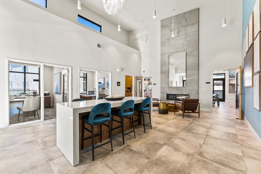 a living room with a bar with blue chairs and a fireplace