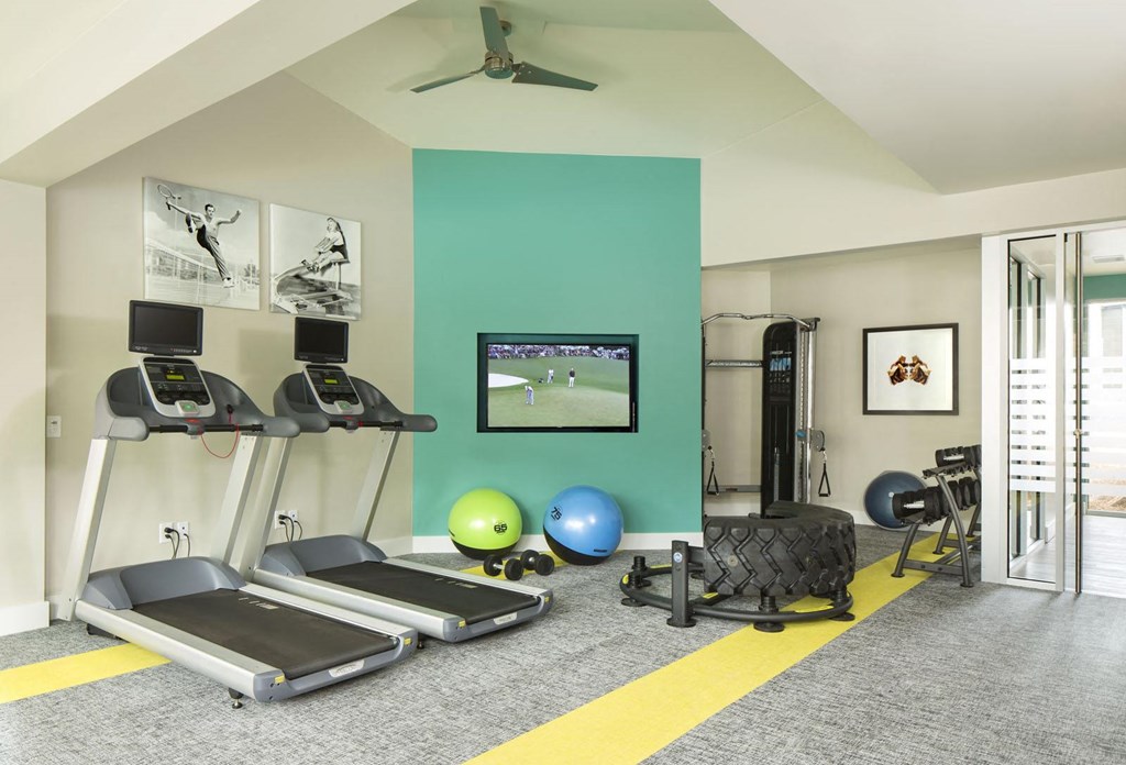 a home gym with a green accent wall and a yellow stripe on the floor