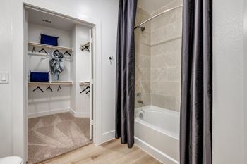 A bathroom with a white tub and a white door with a towel hanging on it.