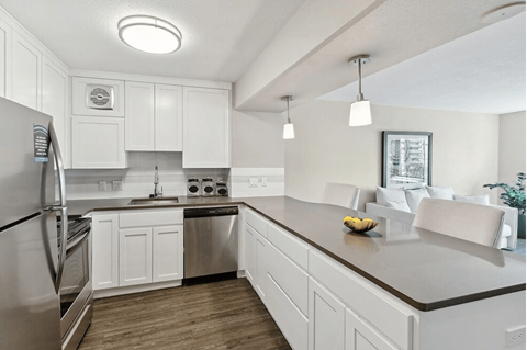 A modern kitchen with white cabinets and a stainless steel refrigerator.