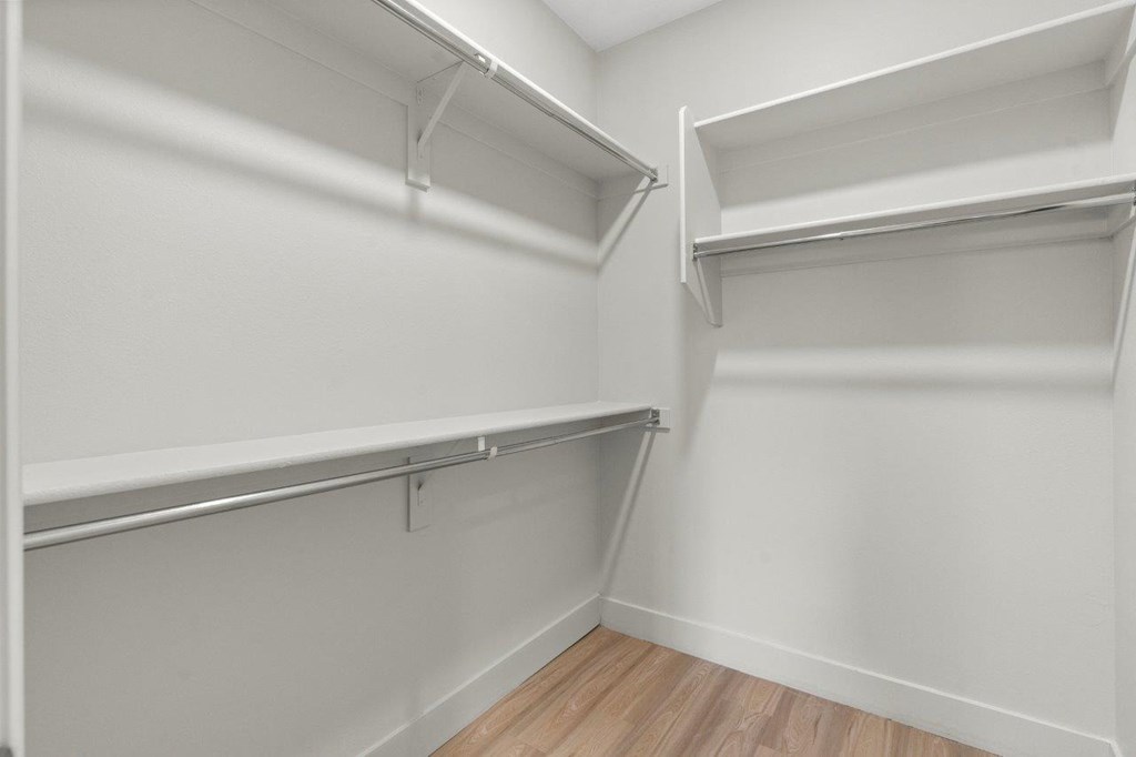 an empty closet with white walls and wood floors
