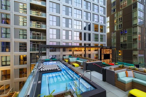 A large indoor swimming pool is surrounded by a lounge area with couches and tables.