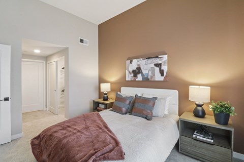 A bedroom with a bed, nightstand, and lamp.
