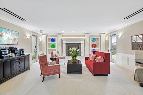 A living room with a red couch, a black coffee table, and a painting on the wall.