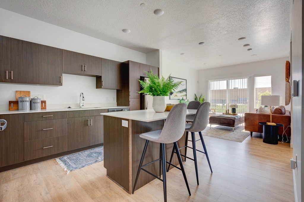a kitchen with a bar and stools in front of a living room