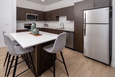 A modern kitchen with a white table and grey chairs.