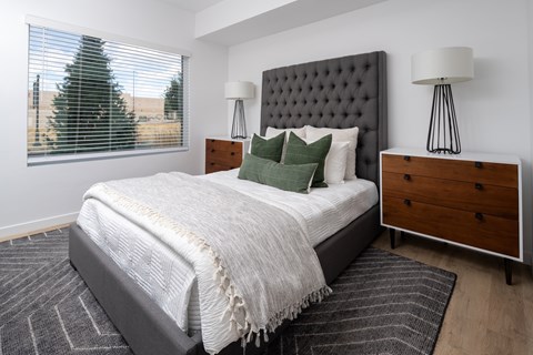 A bedroom with a large bed, a wooden dresser, and two lamps.