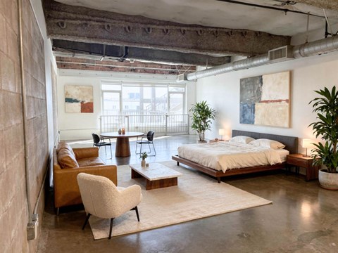 A bedroom with a bed, chair, and a table.