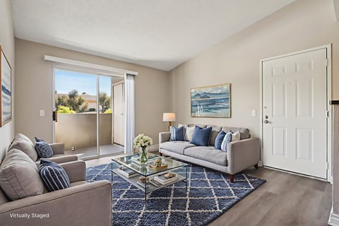 A living room with a grey couch and a painting on the wall.