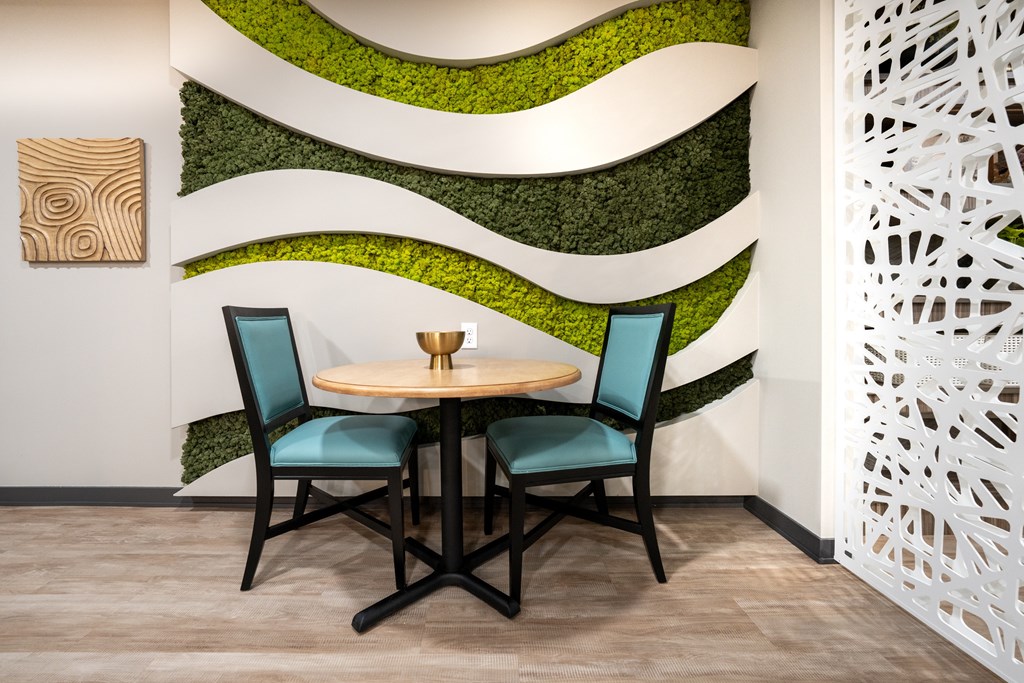A dining table with two chairs in front of a green wall.