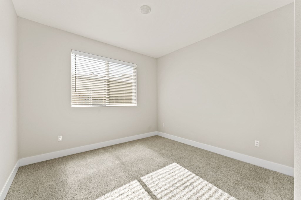 an empty room with a window and carpet