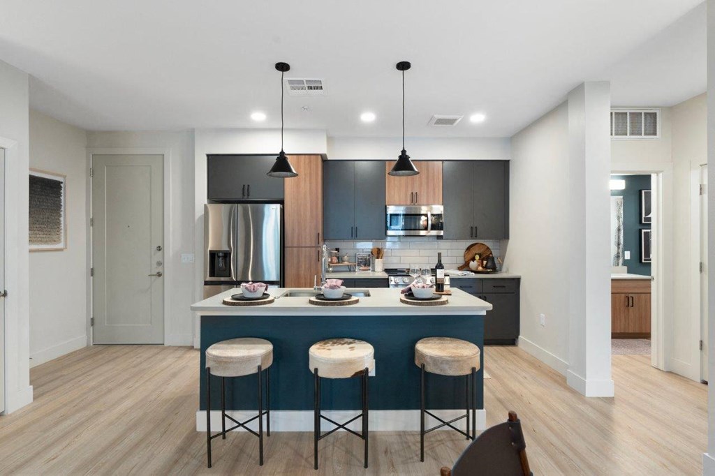 a kitchen with a blue island with three stools