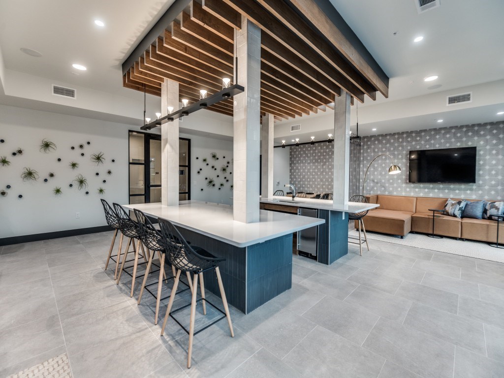 A modern kitchen with a bar area and a TV mounted on the wall.