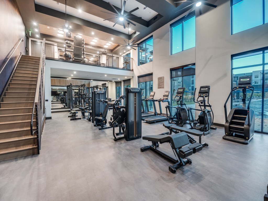 A spacious gym with a variety of equipment and a staircase.