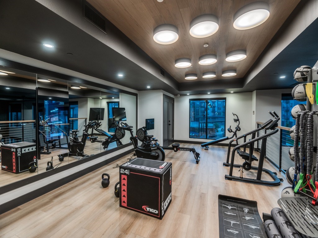 A gym with a variety of equipment including a treadmill, weights, and a bench press.