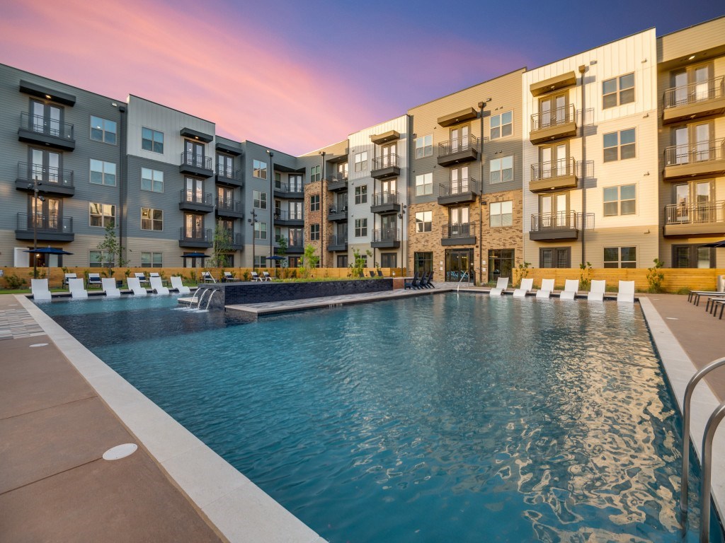 A swimming pool is surrounded by apartment buildings.