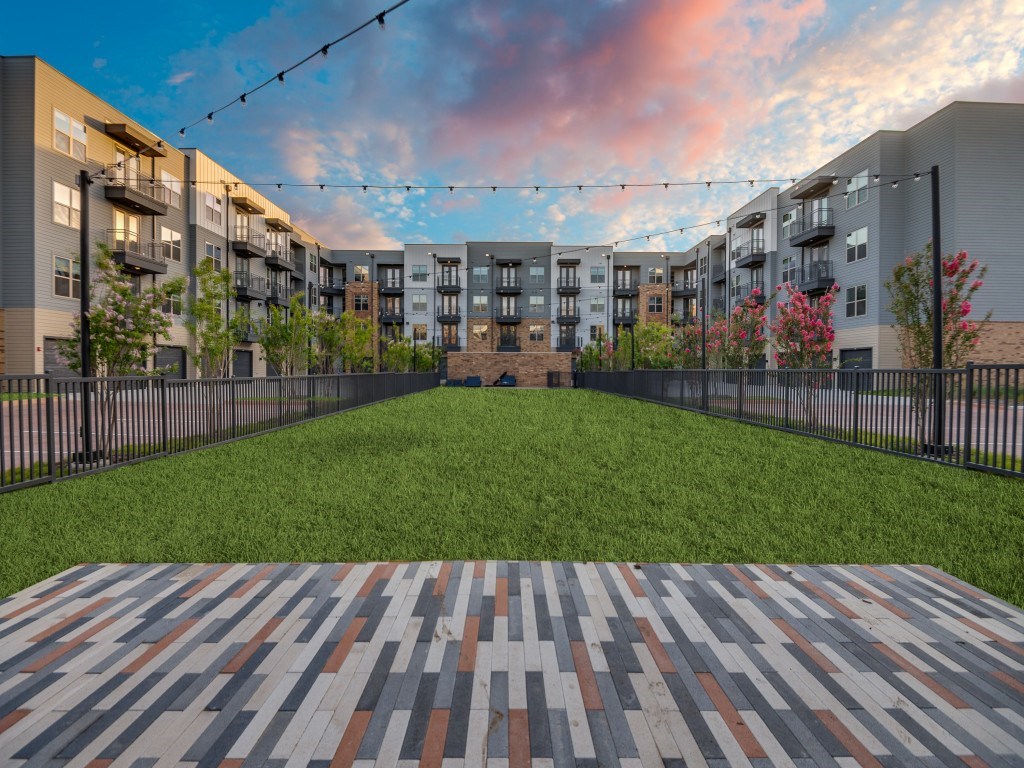 A courtyard with a brick walkway and a fence with flowering trees.