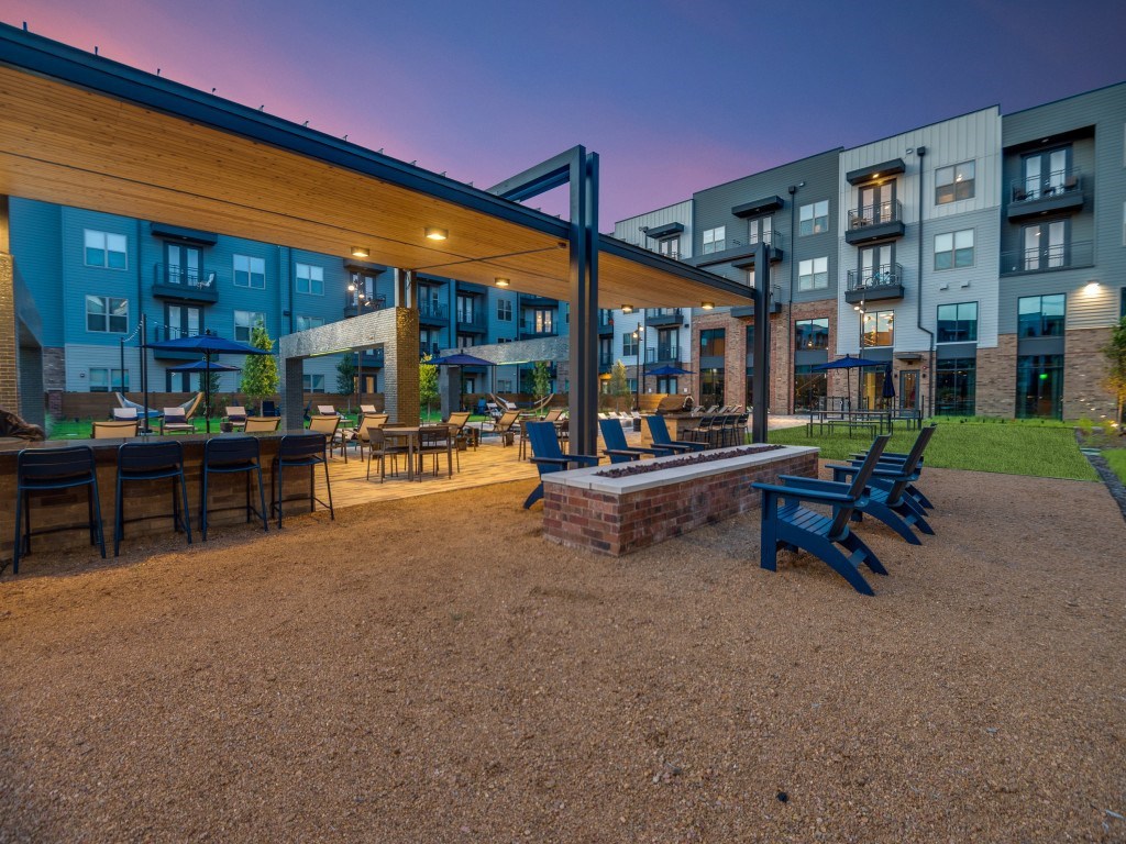 A patio area with a table and chairs is surrounded by apartment buildings.