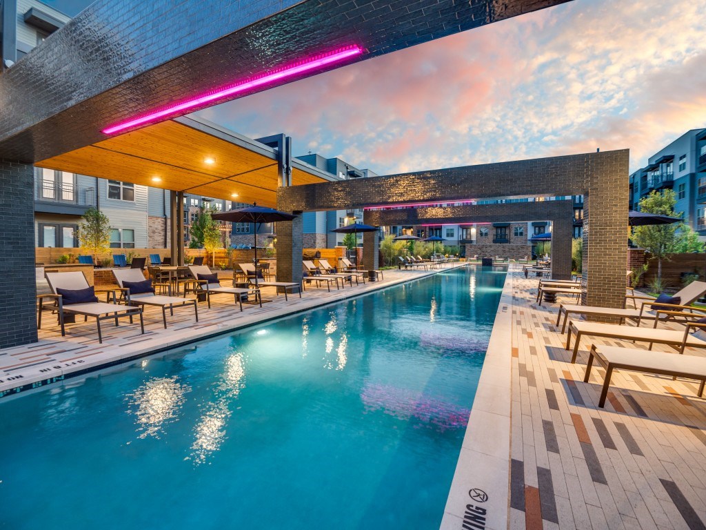 A modern pool area with a long rectangular pool and a long wooden bench on the side.