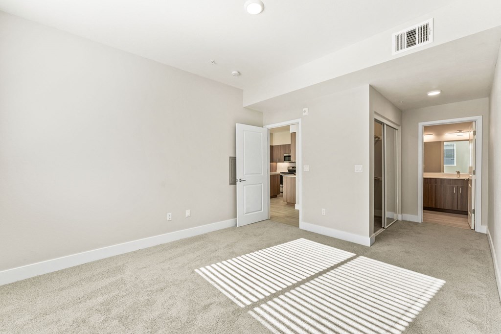 a spacious living room with carpet and a door to a kitchen